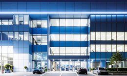 High-Tech Hospital Facade with Blue Glass & Illuminated Night Identity